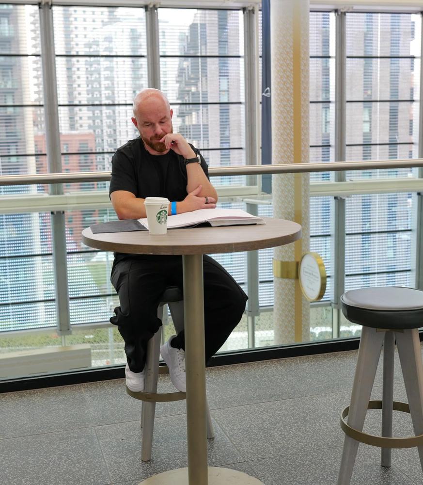 Luke Staton preparing notes at a cafe table before a talk.